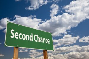 A green sign with "Second Chance" against a cloudy sky. Could relate to finding a job with a criminal record.