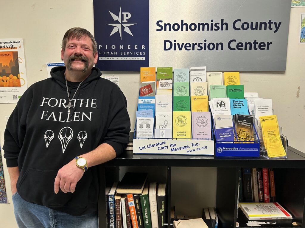 A person stands by a literature display at a Snohomish County Diversion Center, promoting a journey to recovery.