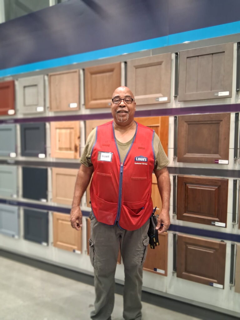 A person in a red vest stands in front of a display of cabinet doors at a store.