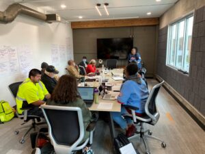 A group of people sit in a meeting room, engaged in a workshop or discussion.