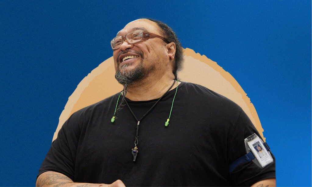 Man smiling with an orange circle and blue background behind him.