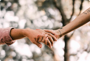 Two hands holding together with a nature background behind.